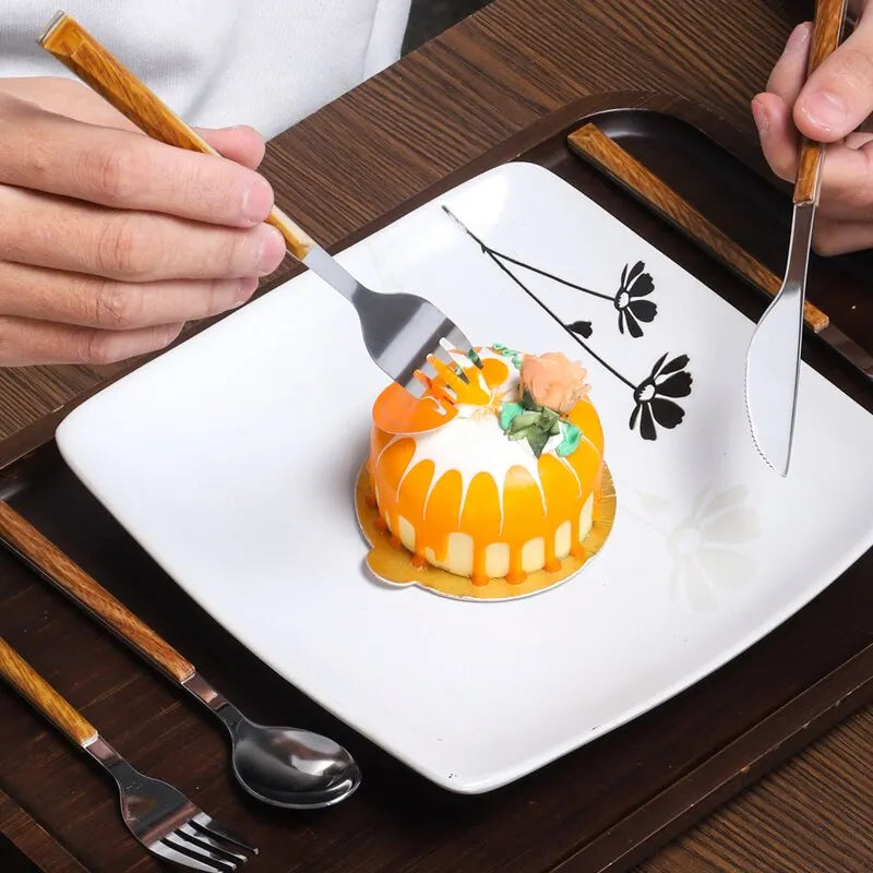 person using Wood Handle Cutlery Set to cut into a desert