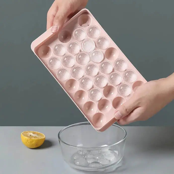 person pouring ice from a Round Ice Ball Mold into a bowl